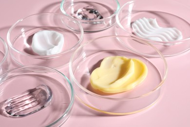 Photo of Different cosmetic products in Petri dishes on pink background, closeup