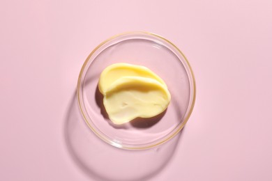 Photo of Cosmetic product in Petri dish on pink background, top view