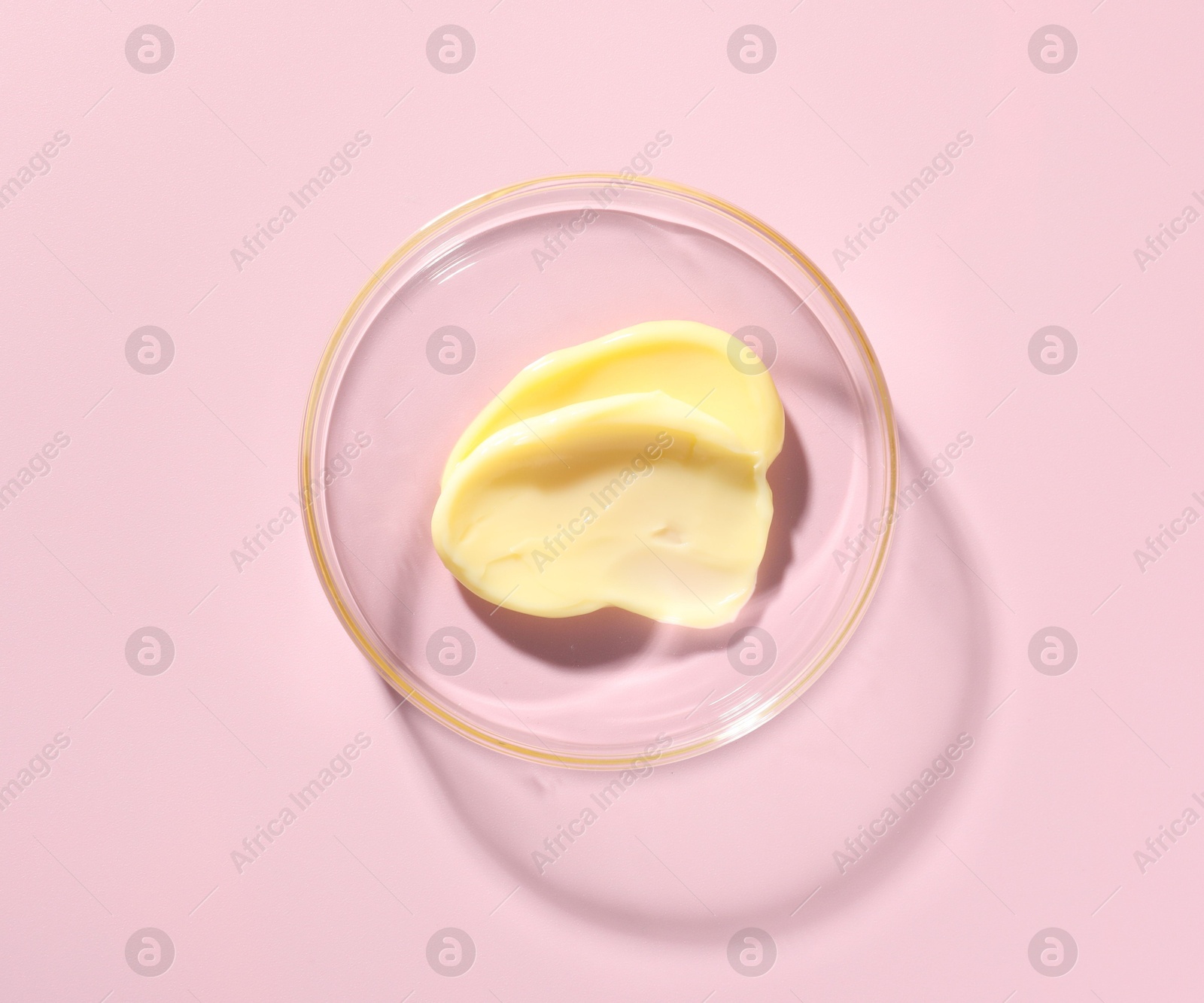 Cosmetic product in Petri dish on pink background, top view Photo of Cosmetic product in Petri dish on pink background, top view