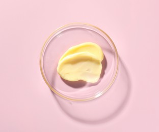 Photo of Cosmetic product in Petri dish on pink background, top view