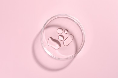 Photo of Cosmetic product in Petri dish on pink background, top view
