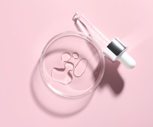 Photo of Cosmetic product in Petri dish and dropper on pink background, flat lay