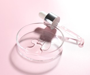 Photo of Cosmetic product in Petri dish and dropper on pink background, closeup