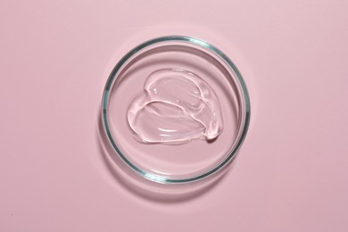 Photo of Cosmetic product in Petri dish on pink background, top view