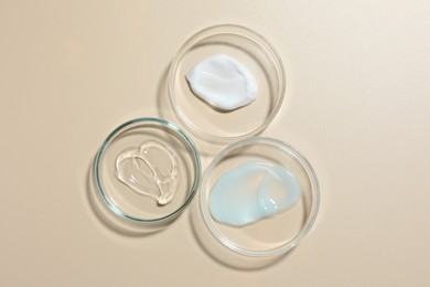Photo of Different cosmetic products in Petri dishes on beige background, flat lay