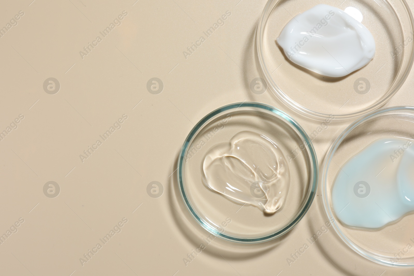 Different cosmetic products in Petri dishes on beige background, flat lay. Space for text Photo of Different cosmetic products in Petri dishes on beige background, flat lay. Space for text