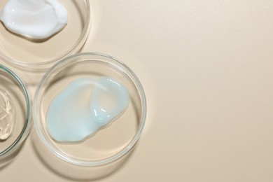 Photo of Different cosmetic products in Petri dishes on beige background, flat lay. Space for text
