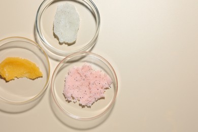 Photo of Different cosmetic products in Petri dishes on beige background, flat lay. Space for text
