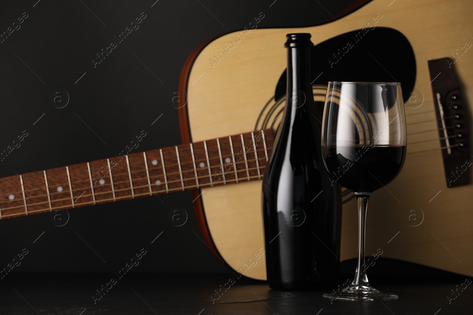 Acoustic guitar and red wine on black table, closeup Photo of Acoustic guitar and red wine on black table, closeup