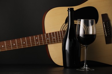 Photo of Acoustic guitar and red wine on black table, closeup
