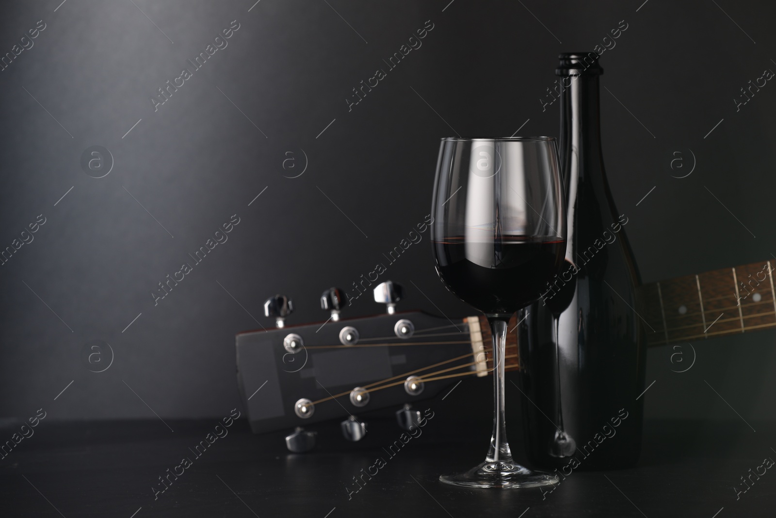 Acoustic guitar and red wine on black table, closeup. Space for text Photo of Acoustic guitar and red wine on black table, closeup. Space for text