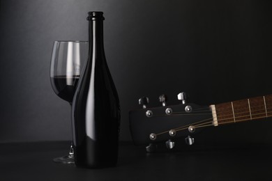 Photo of Acoustic guitar and red wine on black table, closeup. Space for text