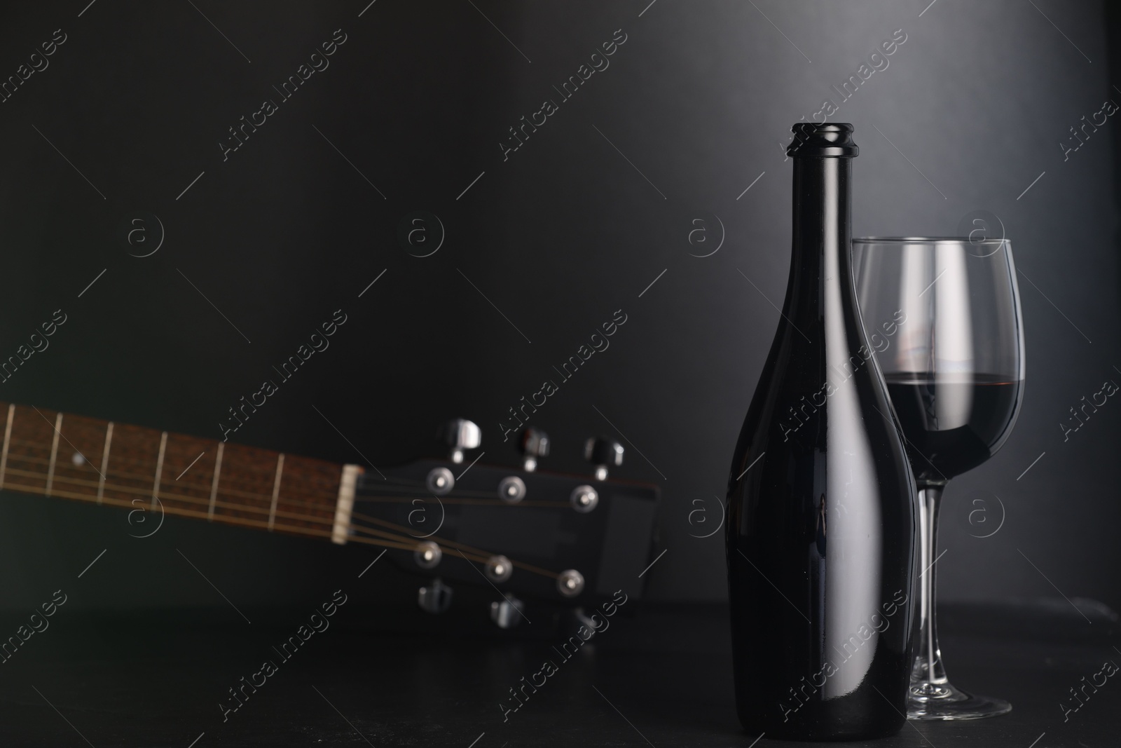 Acoustic guitar and red wine on black table. Space for text Photo of Acoustic guitar and red wine on black table. Space for text