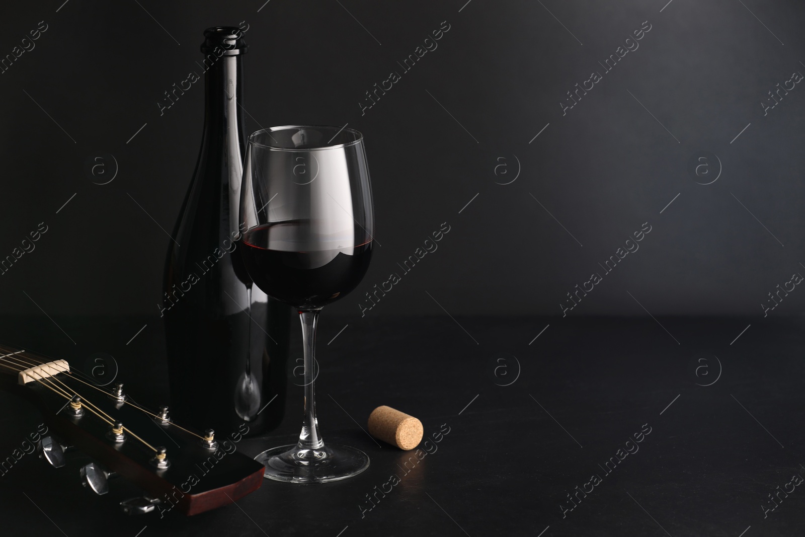 Acoustic guitar and red wine on black table. Space for text Photo of Acoustic guitar and red wine on black table. Space for text