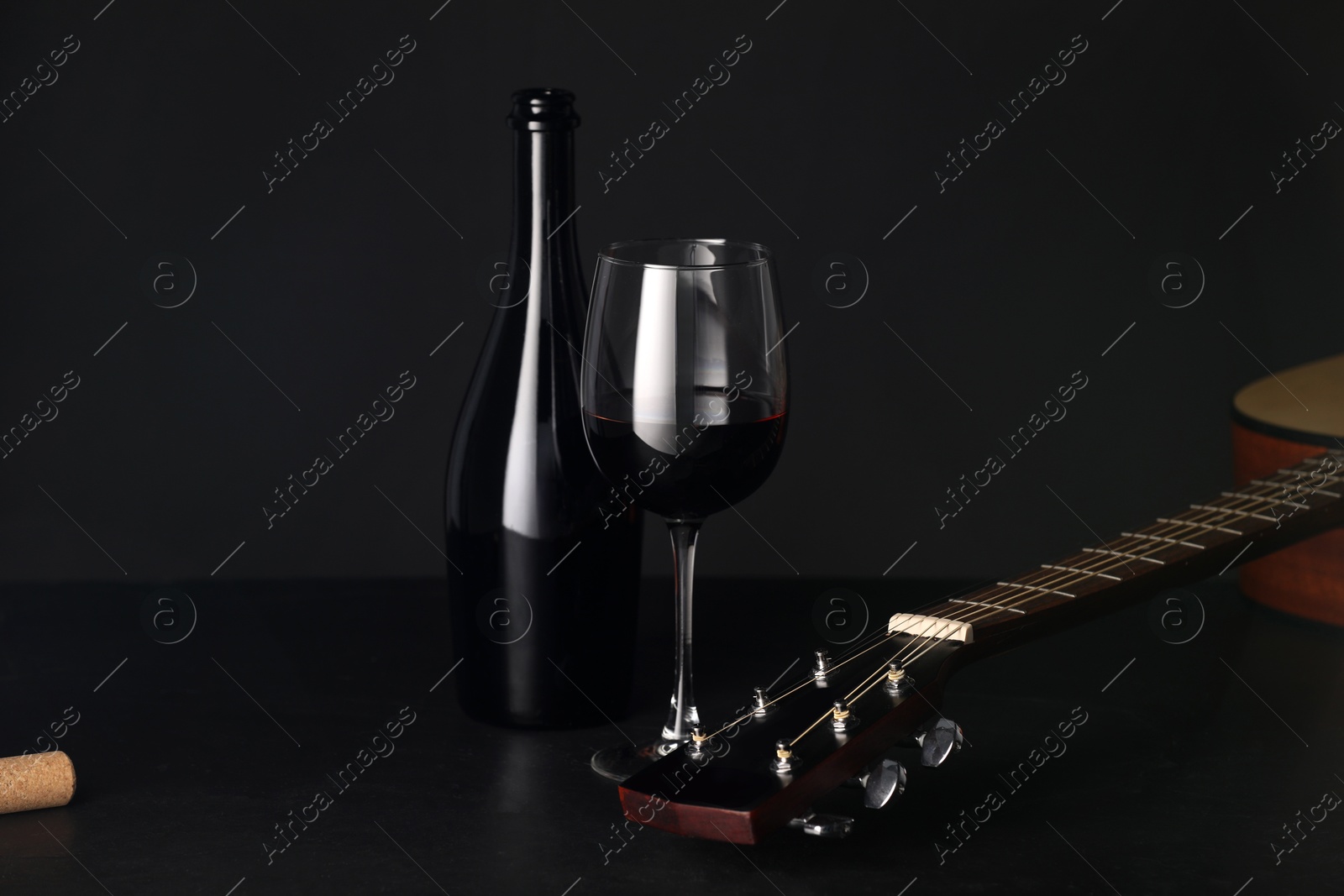 Acoustic guitar and red wine on black table, closeup Photo of Acoustic guitar and red wine on black table, closeup