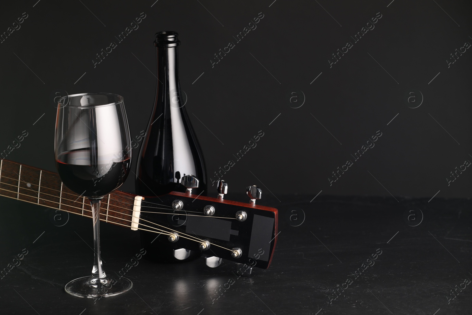 Acoustic guitar and red wine on black table, closeup. Space for text Photo of Acoustic guitar and red wine on black table, closeup. Space for text
