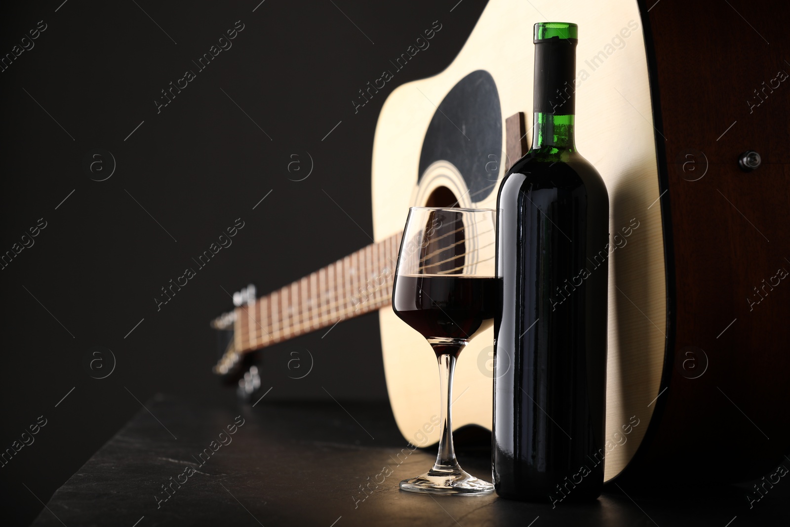 Acoustic guitar and red wine on black table, closeup Photo of Acoustic guitar and red wine on black table, closeup