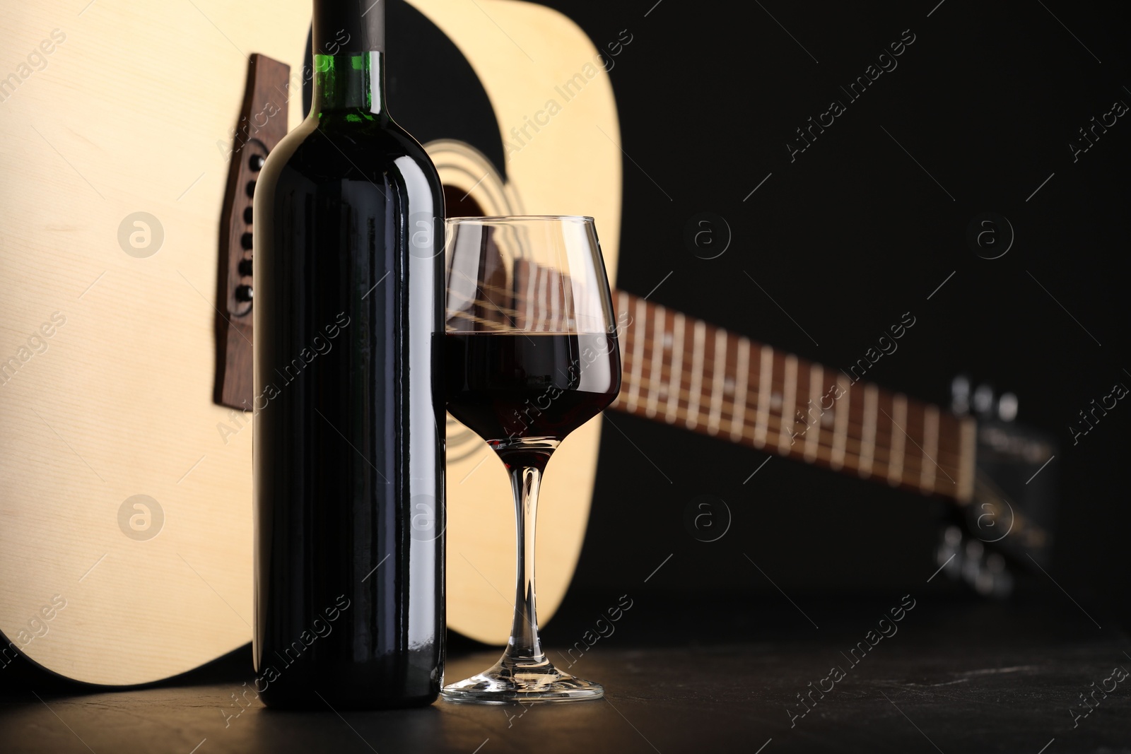 Acoustic guitar and red wine on black table, closeup Photo of Acoustic guitar and red wine on black table, closeup