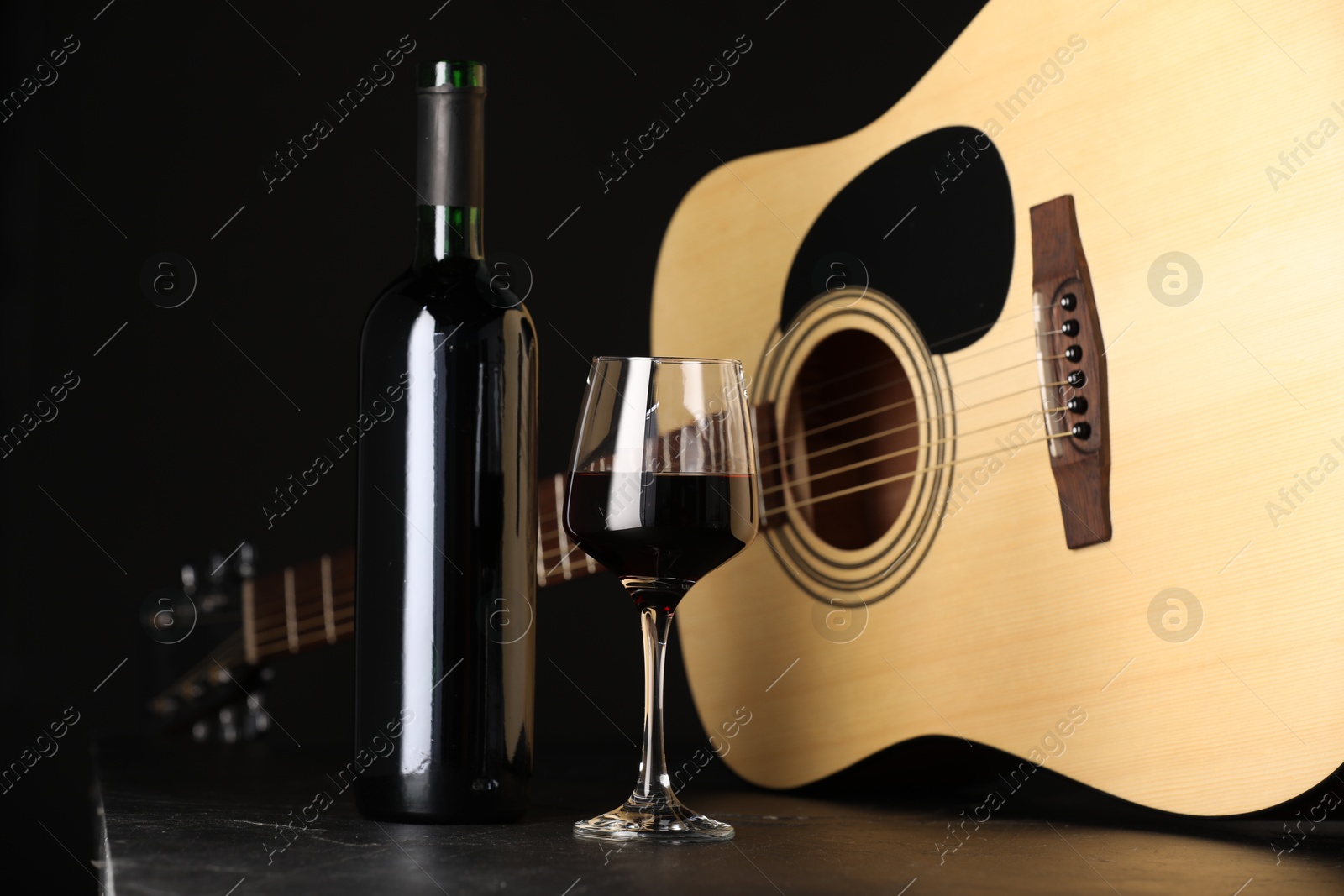 Acoustic guitar and red wine on black table, closeup Photo of Acoustic guitar and red wine on black table, closeup