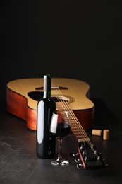 Photo of Acoustic guitar and red wine on black table, closeup. Space for text