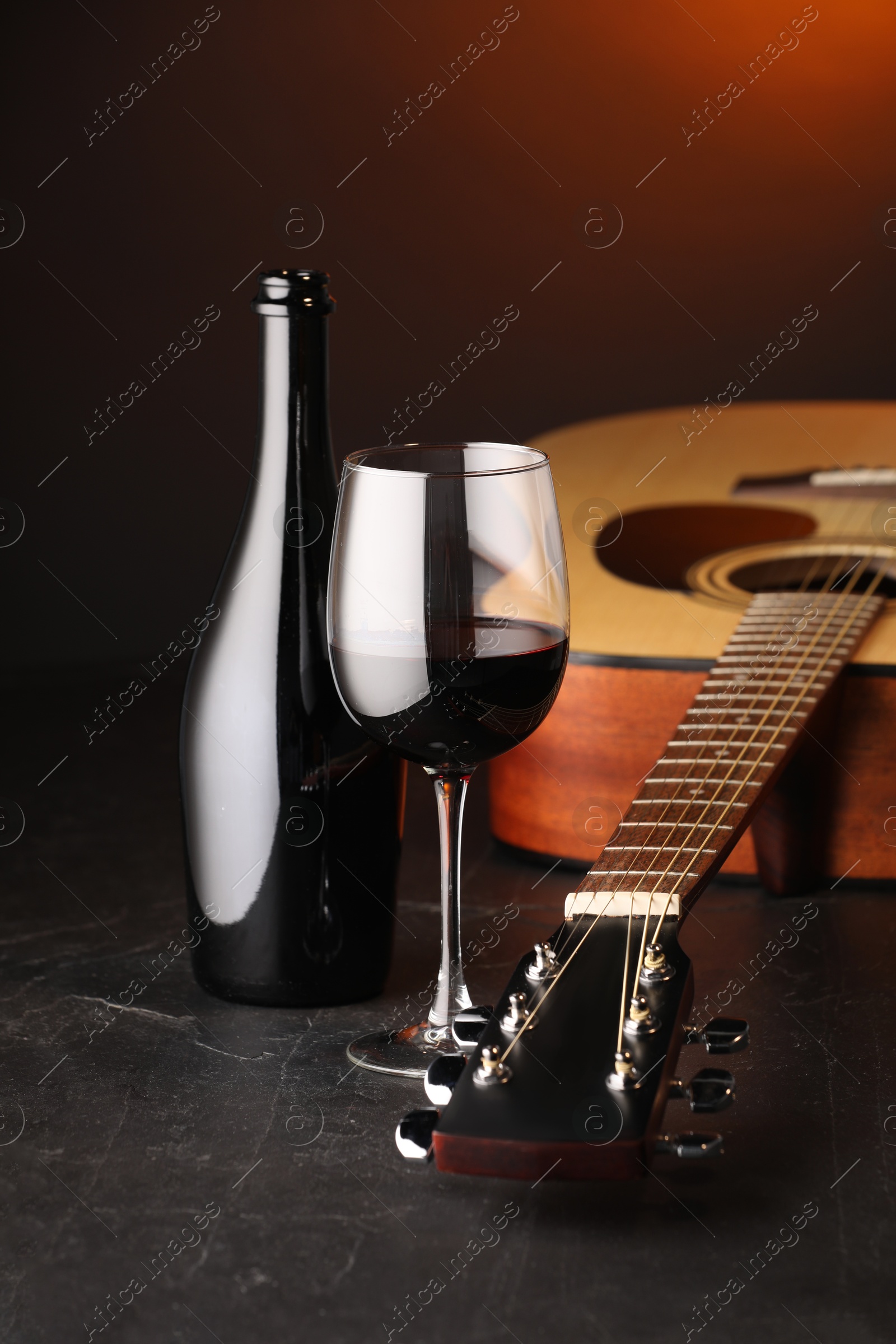 Acoustic guitar and red wine on black table with brown light, closeup Photo of Acoustic guitar and red wine on black table with brown light, closeup