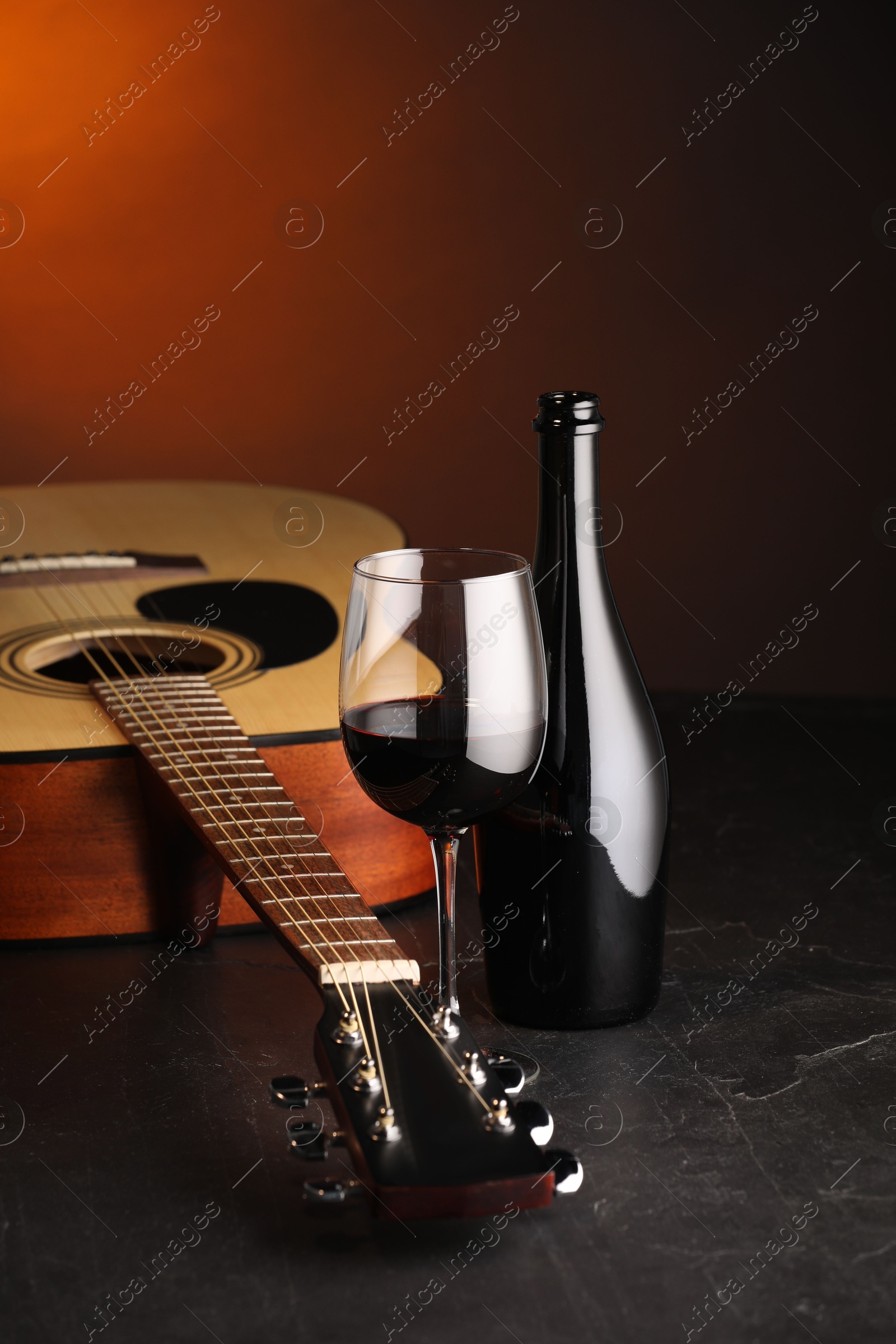 Acoustic guitar and red wine on black table with brown light, closeup Photo of Acoustic guitar and red wine on black table with brown light, closeup