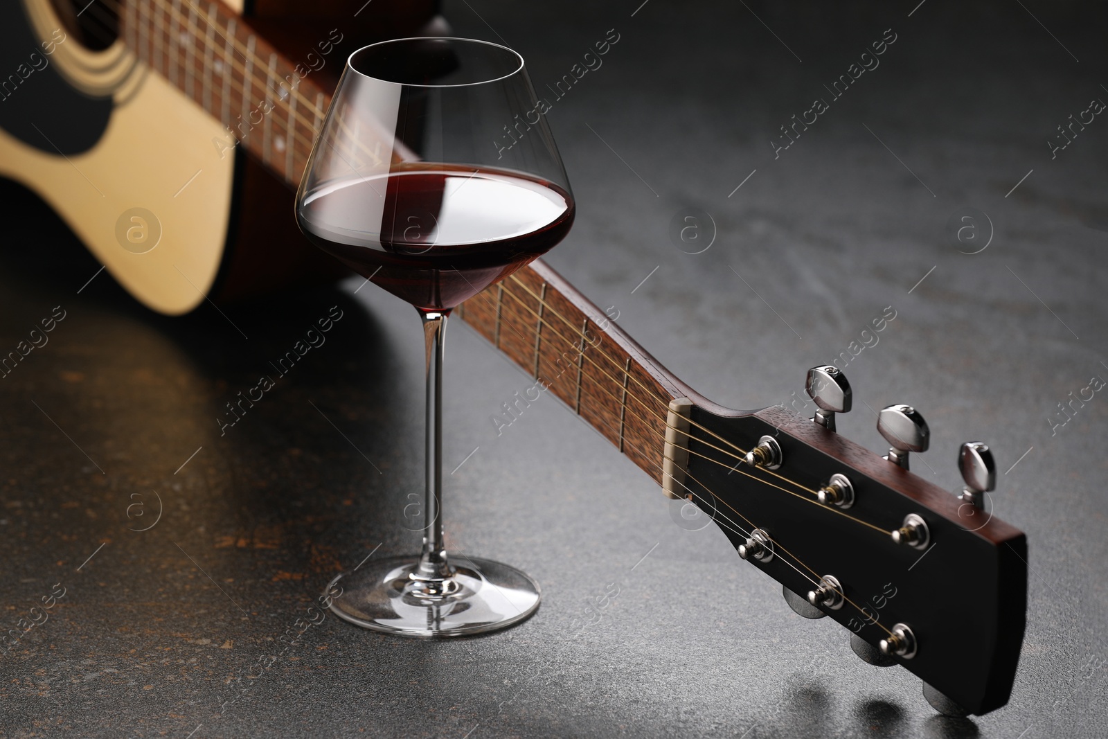 Acoustic guitar and red wine on black table, closeup Photo of Acoustic guitar and red wine on black table, closeup