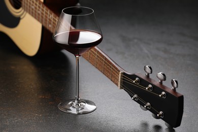 Photo of Acoustic guitar and red wine on black table, closeup