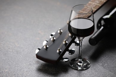 Photo of Acoustic guitar and red wine on black table, closeup. Space for text