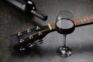 Photo of Acoustic guitar and red wine on black table, closeup