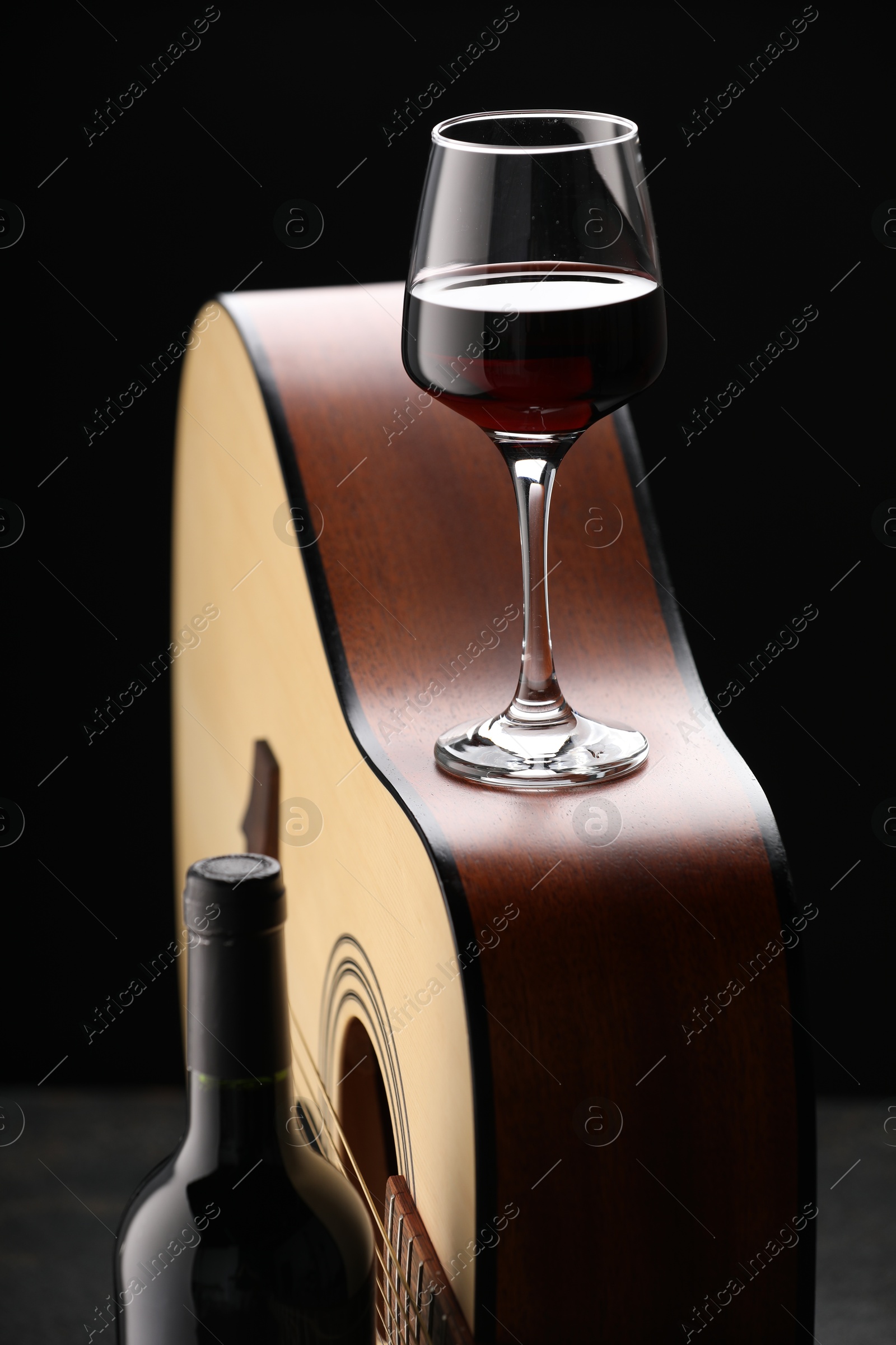Acoustic guitar and red wine on black table, closeup Photo of Acoustic guitar and red wine on black table, closeup
