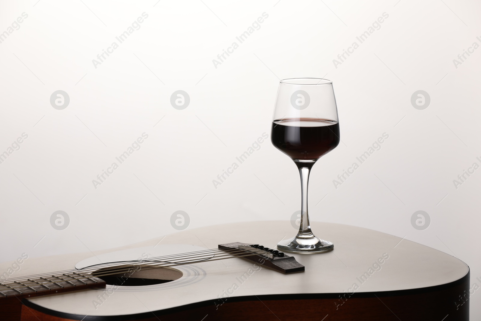 Acoustic guitar and red wine on white background, closeup. Space for text Photo of Acoustic guitar and red wine on white background, closeup. Space for text