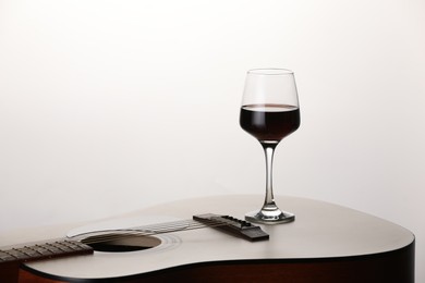 Photo of Acoustic guitar and red wine on white background, closeup. Space for text