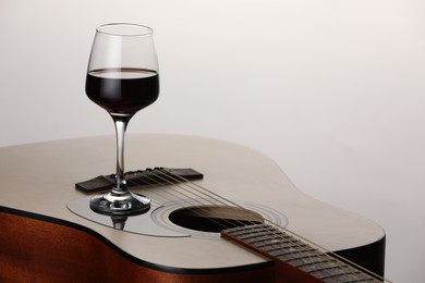 Photo of Acoustic guitar and red wine on white background, closeup. Space for text