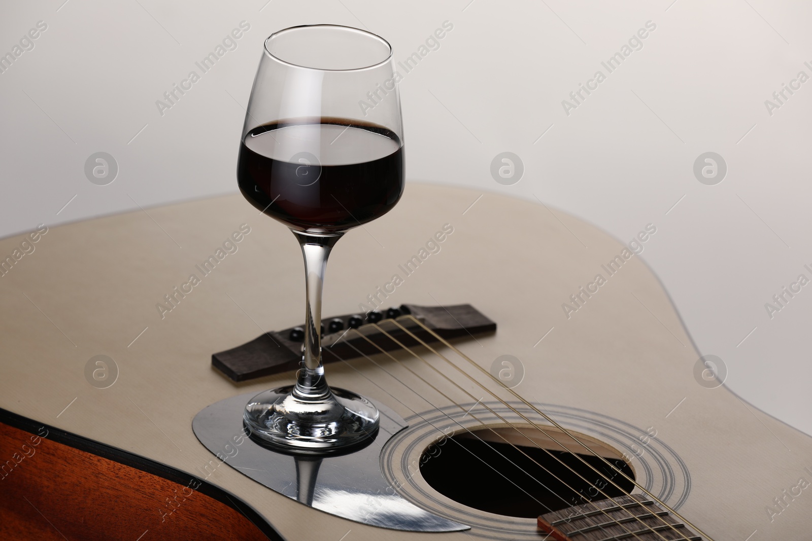 Acoustic guitar and red wine on white background, closeup Photo of Acoustic guitar and red wine on white background, closeup