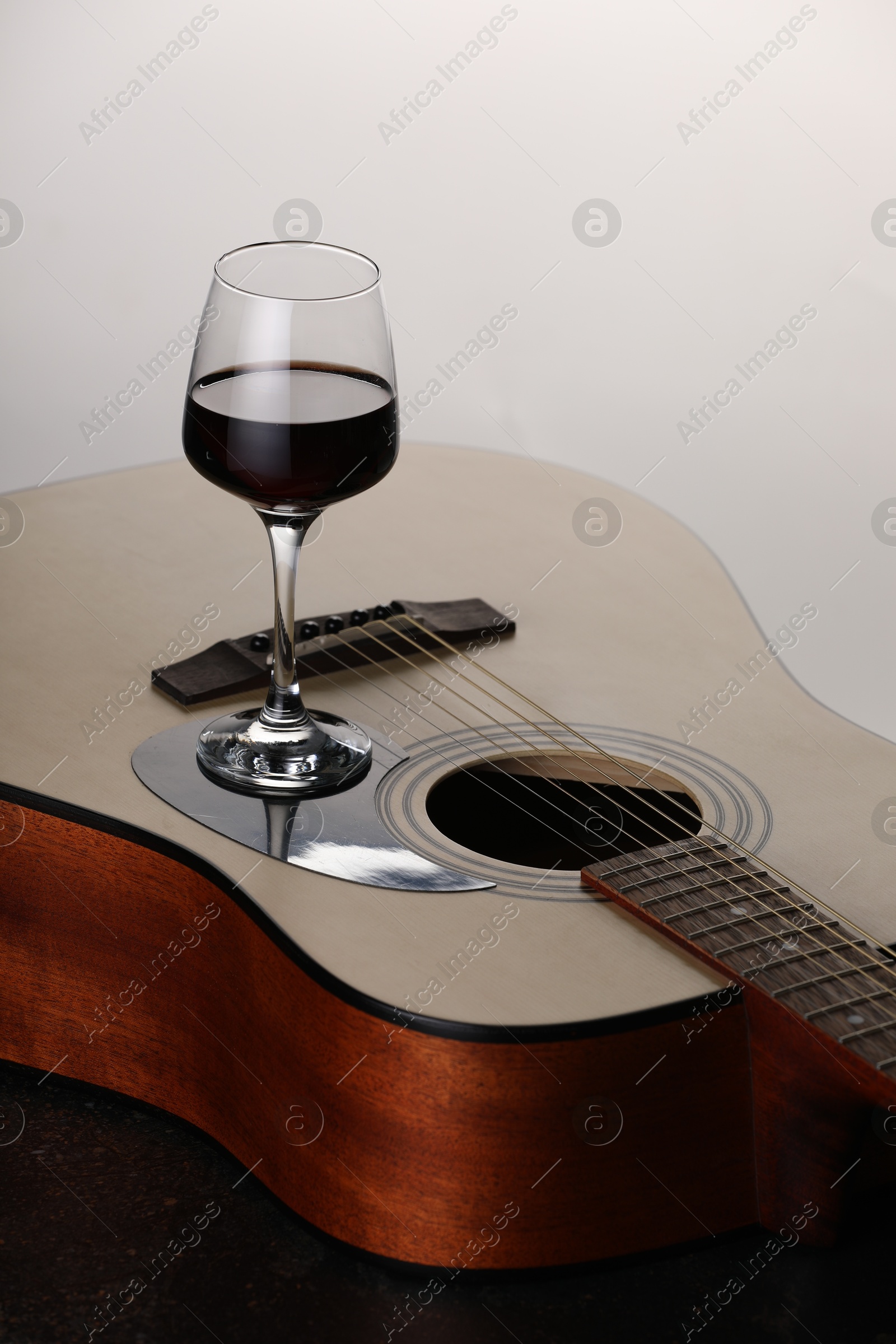 Acoustic guitar and red wine on white background, closeup Photo of Acoustic guitar and red wine on white background, closeup