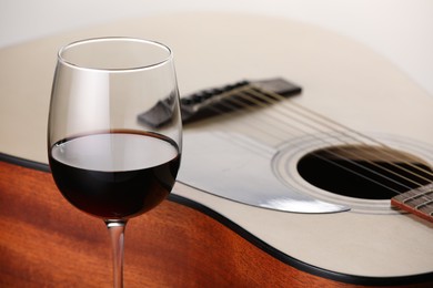 Photo of Acoustic guitar and red wine on white background, closeup