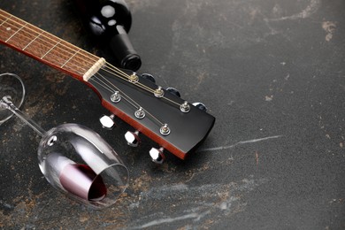 Photo of Acoustic guitar and red wine on black table, closeup. Space for text