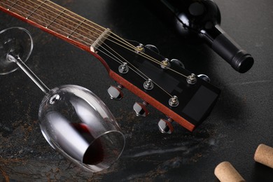 Photo of Acoustic guitar and red wine on black table, closeup