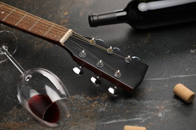 Photo of Acoustic guitar and red wine on black table, closeup