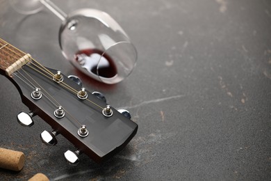 Photo of Acoustic guitar and red wine on black table, closeup. Space for text