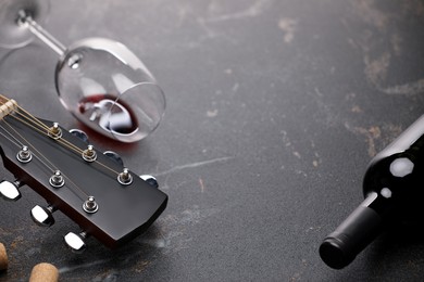 Photo of Acoustic guitar and red wine on black table, closeup. Space for text