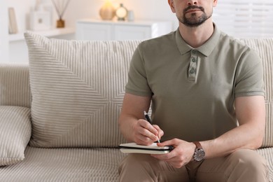 Photo of Professional psychologist with notebook on sofa in office, closeup