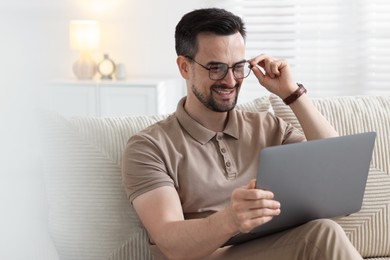 Photo of Professional psychologist having online consultation with his client via laptop on sofa indoors