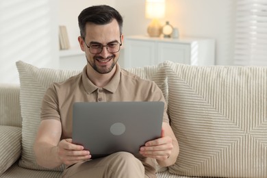 Photo of Professional psychologist having online consultation with his client via laptop on sofa indoors