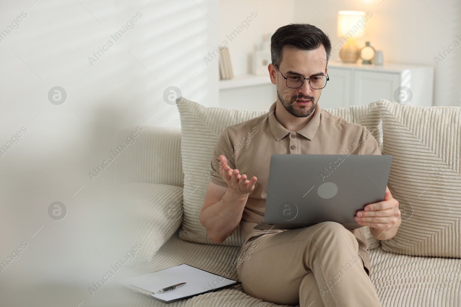 Professional psychologist having online consultation with his client via laptop on sofa indoors. Space for text Photo of Professional psychologist having online consultation with his client via laptop on sofa indoors. Space for text