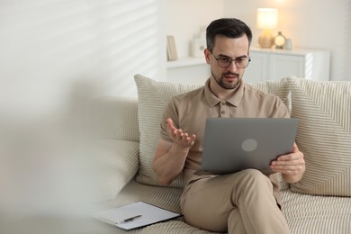 Photo of Professional psychologist having online consultation with his client via laptop on sofa indoors. Space for text