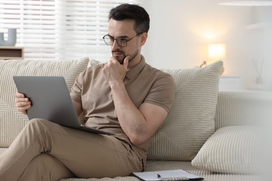 Photo of Professional psychologist having online consultation with his client via laptop on sofa indoors