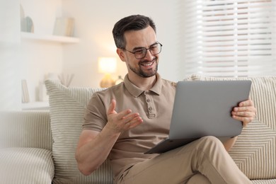 Photo of Professional psychologist having online consultation with his client via laptop on sofa indoors