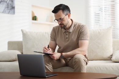 Photo of Professional psychologist having online consultation with his client via laptop on sofa indoors